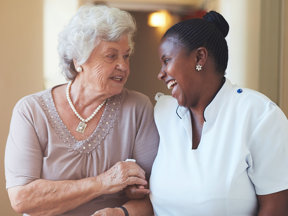 A image of a senior having a conversation with an assisted living employee.
