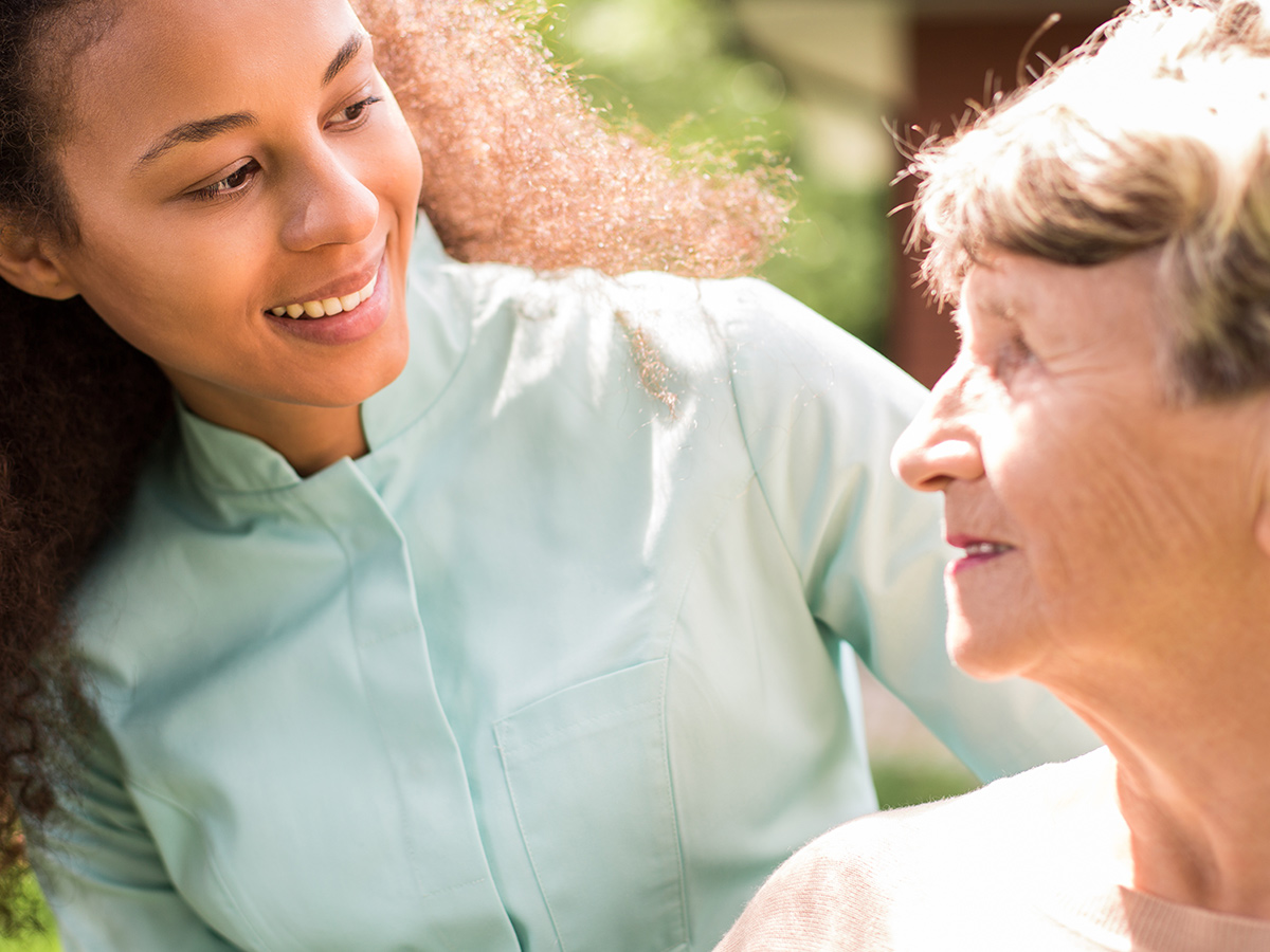 An image of an assisted living assistant and a senior enjoying the outdoors.